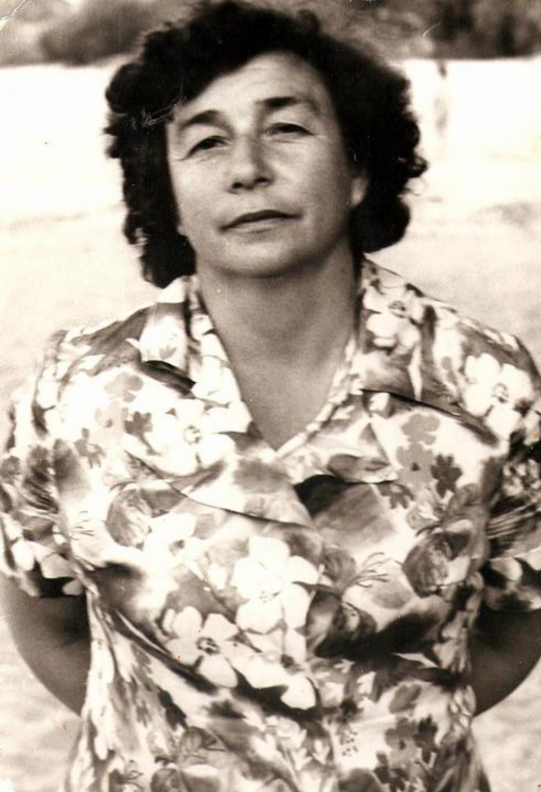 Bronia Furman Berdichevsky in a floral blouse, standing outdoors